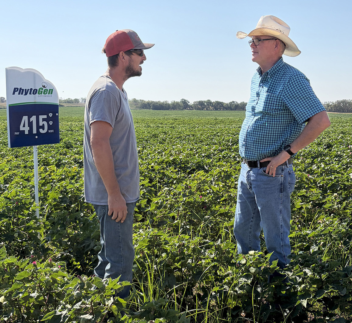 Collingsworth County producer Sonny Cox, left, converses with AgriLife Extension Weed Specialist Peter Dotray amongst the blooming cotton trial plots on the western edge of Rex Henard’s water-saving pivot irrigation system during the Sept. 4 crops tour. INTREPID PHOTO / BEV ODOM