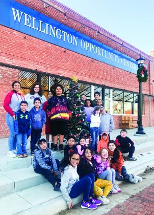 Several Wellington Opportunity Center, Inc. (WOCI) students and staff gather around the Christmas tree on the westside of the Collingsworth County Courthouse Square prior to dismissal of the fall session. Contributions to WOCI can be mailed to P.O. Box 122, Wellington, TX 79095. The Red River Sun/Bev Odom