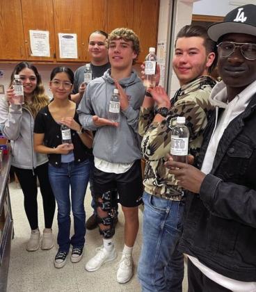 Wellington High School (WHS) organizations benefit from the donation of water bottles by Wellington State Bank (WSB). The water is being used basketball concession stands all season long. Juniors displaying bottles, containing the WSB logo, at the Tuesday, Jan. 31 WHS Class of 2024 fundraiser include Jacqueline Garcia, left, Brianna Aguero, Tristan Hamby, Dakota Marshall, Brandon Cooper and Calvin Brewer. Courtesy Photo