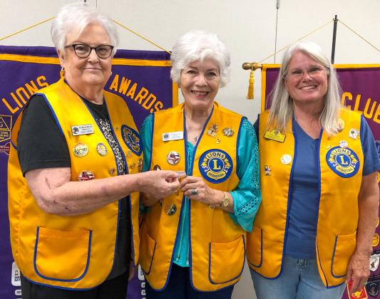 During the July 21 meeting of the Wellington Lions Club, Lion Linda Powell, center, accepts her 10-year-pin. Lion Nancy Harris makes the presentation, along with Boss Lion Lori O’Rear.