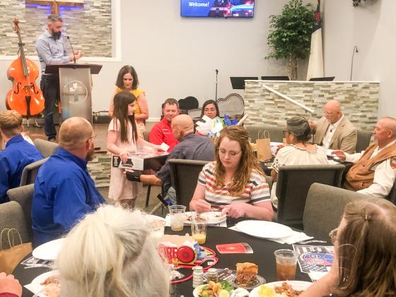 Assisting organizer Karrie Hudson, Penny Downing presents Collingsworth County Constable Cliff Waller a door prize as Pastor Noah Downing calls his name during the recent Calvary Baptist Church First Responder Appreciation Dinner.