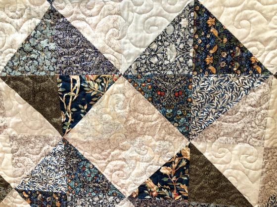 The beautiful keepsake quilt is described by its creator, Gwynna Waller, as “restful to the eyes — something we can just relax with in our crazy world.” The simple half square triangle quilt features decorative art textiles of Morris &amp; Co., founded in 1861 by William Morris. Inspired by nature and early examples of woven textiles he studied at museums, Morris’ designs are famous for their intricate, naturalistic patterns inspired by flora and fauna.