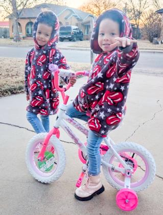 Amiyah Stanley, alongside her twin sister, Armani, takes her new bike for a test ride. The daughters of Cody Stanley, Amiyah won the girl’s bicycle drawing during the Saturday evening, Dec. 6 Collingsworth County Chamber of Commerce Christmas on the Bricks event.