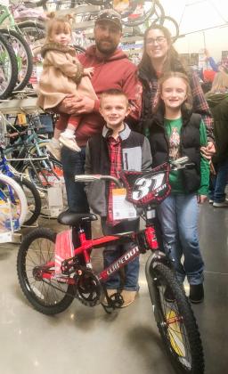 Mack Tarver, accompanied by little sister Rebekah, parents Matt and Addie and big sister Katie, chooses his boy’s bicycle prize he won during the recent Collingsworth County Chamber of Commerce Lighting of the Square occasion.