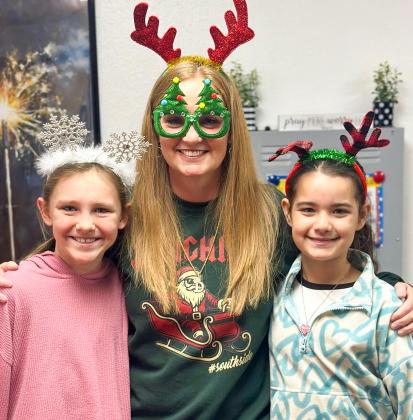Wellington Elementary School Principal Deidre Kane gathers with fifth-graders Raylie Sims, left, and Summer Valles on Thursday, Dec. 18 for “Holiday Headgear… Spread the Cheer!” prior to the Friday, Dec. 19 release for the Christmas holiday. Teachers return to work Monday, Jan. 5, while students return Tuesday, Jan. 6.