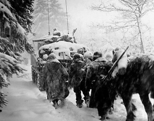 The 82nd Airborne troops travel on foot in the snow behind a 740th tank advancing to Herresbach.