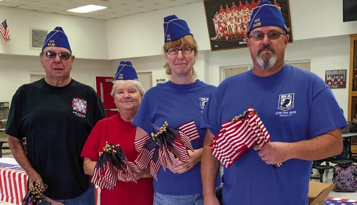Upon entry to the Veterans Day event, Bruce and Diane Vanderplaats and Dawn and Shane Popwell, members of Glynn Moore VFW Post 6439 Auxiliary, present each visitor a U.S. flag. Courtesy Photo