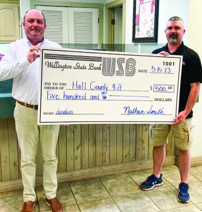 Hall County 4-H, represented by Christian Brooks, left, accepts a $500 donation from Wellington State Bank Senior Vice President Nathan Smith Monday, May 15. Photo Courtesy of Hall County 4-H