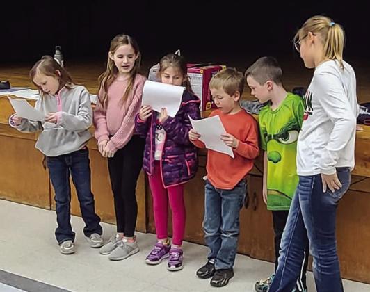 First-graders Kaizley Byers, left, Blair Ward, Jenna Faulks, Jackson Smith and Kacen Wiebe present honeybee facts under the guidance of fifth-grader Ava Kate Inman.