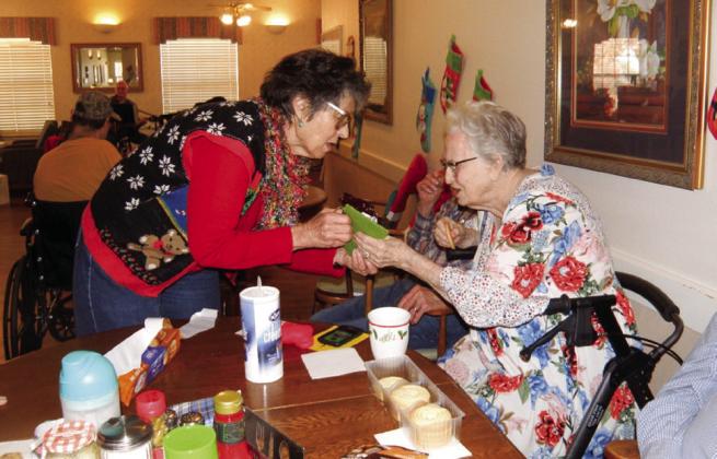 Rothwell Circle of United Women in Faith of Childress Methodist Church member Lila Hoobler presents Cottage Village Assisted Living and Retirement Center resident Billie Simmons a stocking at the Christmas party Tuesday, Dec. 14. Grace Holman Photos