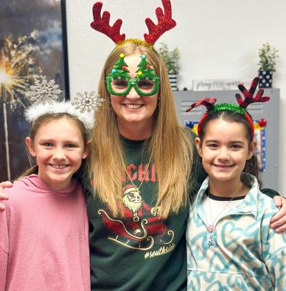 Wellington Elementary School Principal Deidre Kane gathers with fifth-graders Raylie Sims, left, and Summer Valles on Thursday, Dec. 18 for “Holiday Headgear… Spread the Cheer!” prior to the Friday, Dec. 19 release for the Christmas holiday. Teachers return to work Monday, Jan. 5, while students return Tuesday, Jan. 6. Wellington Elementary School
