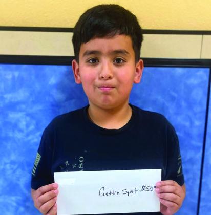 Fourth-grader Andrew Garcia accepts The Gettin’ Spot Café gift certificate on behalf of his dad, Jonathan Skelton.