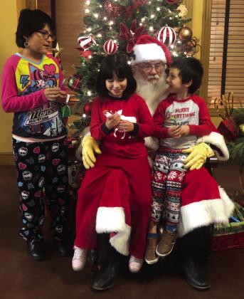 Angelina, 10, Alexia, 6, and Liam, 5, children of Jennifer Nanez and Clint Melton, treasure time with Santa during the annual Merry and Bright PJ Dance Party.