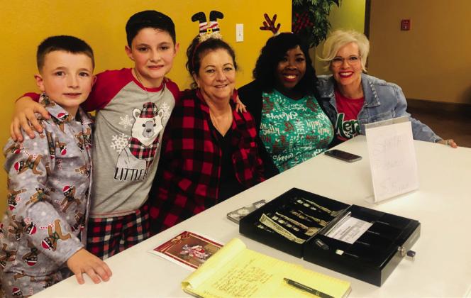 Easton Patterson, left, and Lyric Derr gather with Margret Wood, Brittany Massey and Lyndy Forrester-Black as the women assist Santa with photo requests prior to the Christmas movie.