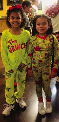 Wellington Elementary firstgraders Aspen Clark, left, and Royalti Navarro wait patiently for popcorn, sporting their Grinch pajamas.