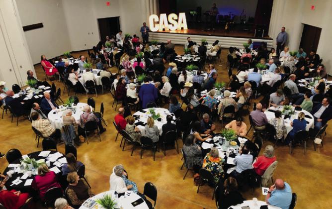 Auctioneer Clay Washington searches for participant bid cards for the drawing by local artist Alesia Freeland during the live auction segment of the Saturday, April 13 CASA Gala. The Red River Sun/Bev Odom