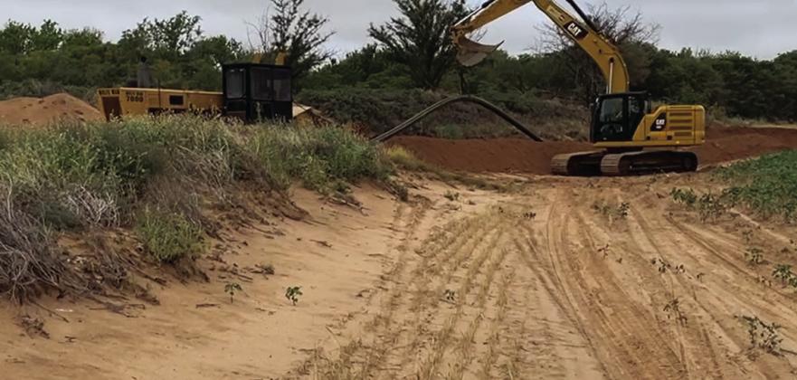 A CAT excavator lifts the poly pipe into the trench for the new pipeline installation in rural Collingsworth County to accomplish the new GreenLight Gas service.