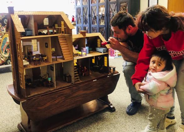 Collingsworth County Museum visitors Enrique Rojas and Stephanie Garcia, along with one-year-old daughter Nevaeh, peer into the dollhouse kit ordered by Phyllis Floyd for her daughters. Purchased from Sears &amp;amp; Roebuck in 1979, her husband, Ray Floyd, had the tedious job of helping assemble the life-like replica. The Red River Sun/Bev Odom