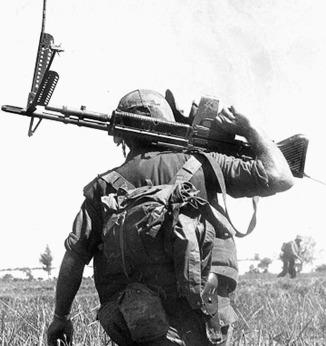A Marine crossing a rice paddy with an M-60 machine gun.