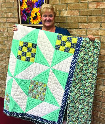 Raffle winner Carol Ann Daves grasps the 2022 Wellington Methodist Women’s turquoise, navy, green and white quilt, constructed and machine quilted by Pastor Gene Weinette and Gwynna “Gigi” Waller. Weinette drew the lucky ticket from almost 2,000 during the Saturday, Nov. 5 Fall Bazaar fundraiser. Courtesy Photo