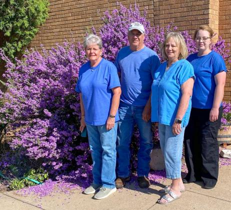 At its best bloom, the SOS from Texas crew admires the vibrant purple blooms of the Texas sage in front of the SOS shop in Samnorwood, headquartered in the former Samnorwood High School. From left: Kathie Lloyd, 15-year employee; owner Gary Oldham; Mona Darrow, 30-year employee; and Allison Bentley, five-year employee. SOS From Texas