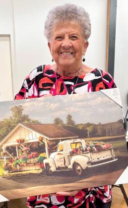 Fraya Hammons claims the grand door prize, a vintage plant-stand print, during the Thursday, March 19 Wellington Senior Citizens Center Plant Swap and Bingo social.