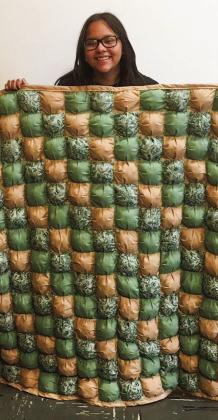 Collingsworth County 4-Her Anna Granadoz displays her finished puff quilt project made of individual squares with a polyester poly-fil in each.