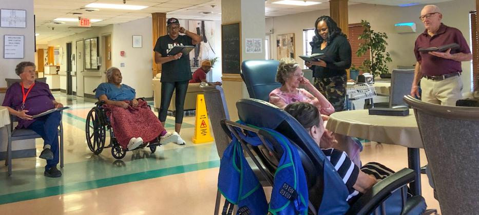 Ninety-five-year-old Harry Stallings, right, directs singing “The Old Rugged Cross” during the Aug. 27 Sunday afternoon worship service at Wellington Care Center. Stallings brought his message from the book of Romans, chapter eight. Visitors joined in leading the hymns. The Red River Sun/Bev Odom
