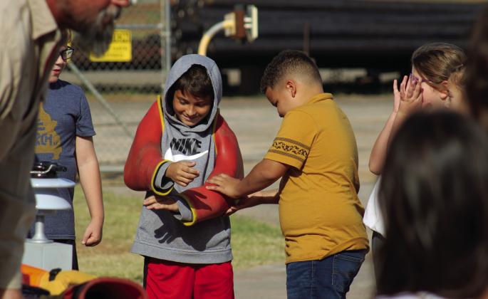 Students try on lineman protective gear, including rubber sleeves, which can withstand up to 30,000 volts of electricity.