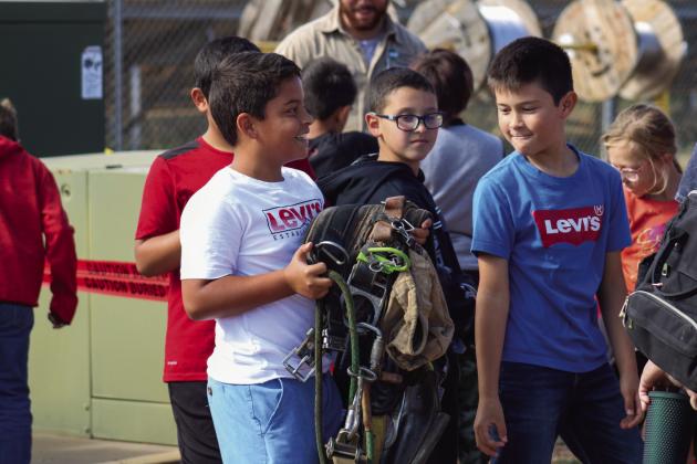 Students examine a lineman’s climbing belt.