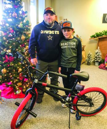 Michael Akemon accompanies his son, Wellington Junior High School sixth-grader Elijah Akemon, to accept the bicycle he won in a drawing during the Lighting of the Square event, presented by Collingsworth County Chamber of Commerce, Saturday, Dec. 3. Courtesy Photos