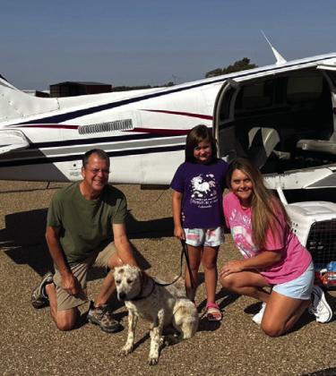 Volunteer pilot Bill Mastin, of Weatherford, delivers Farris from a shelter in East Texas to Wellington Sunday morning, Aug. 4. Wellington Rescue Shelter founder Andi Duke, right, and daughter Sherree, accept delivery of the heeler mix. Courtesy Photo