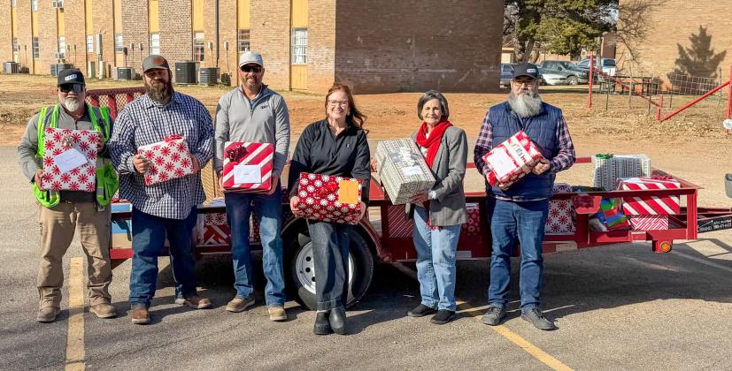 IREN employees, pictured with Childress County Christmas Sharing Board Member Raenell Smith, help deliver gifts to Childress Healthcare Center residents Saturday, Dec. 20.