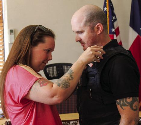 Childress Police Department’s newest officer, Glen Egerton, receives his badge, which is pinned on his vest by his wife, Kendra.