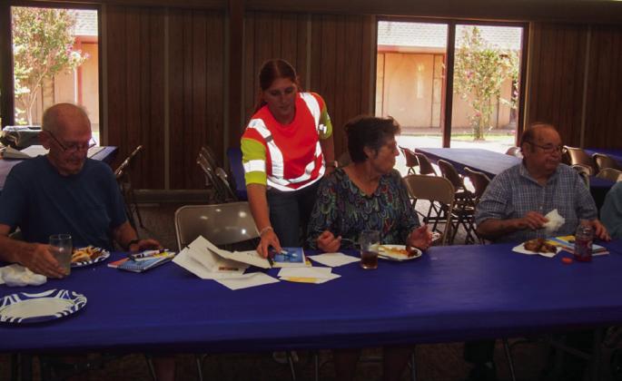 Texas Department of Transportation (TxDOT) Childress District Business Operations Support Technician summer intern Chloe Teichelman distributes handouts at the Adult Fellowship Luncheon at Childress Methodist Church. From left: Jim Dowis, Teichelman, Lila Hoobler, Jerry Duggins.