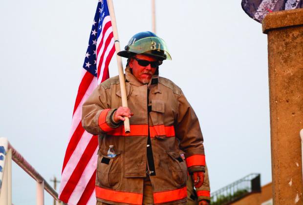 Childress Fire Department firefighter Jimmy Willis carries an American flag during the 9/11 Memorial Stair Climb event in 2021. The Red River Sun/Nicole Dill