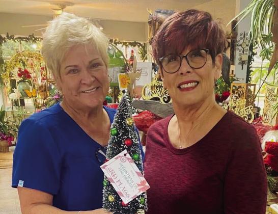 Carol Ann Daves, left, and Annette Bergstrom, accept the third-place tree prize for Carol Ann’s Flowers &amp;amp; Gifts’ sunflower-themed Christmas tree on the northside of the square.