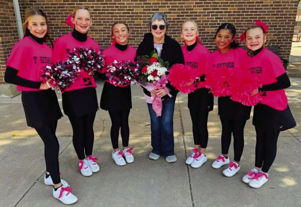 Wellington Junior High School Firecracker cheerleaders and sponsor Heather Proffitt spotlight one of their own, breast cancer survivor Linda Porter, during the pink-out pep rally Thursday, Oct. 17. Porter accepted a bouquet of fresh roses and daisies as a token of their love and support. From left: Libby Chandler, Kaesyn Kane, Claire Kane, Porter, Hartley Kane, Demi Massey and Halle Hedrick. Photo Courtesy of Wellington Junior High School