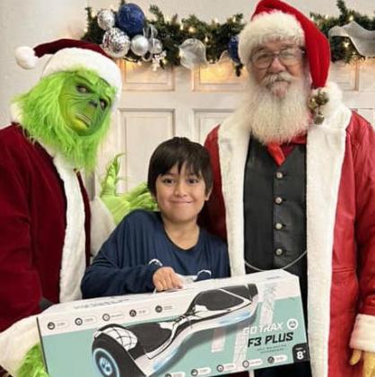 The Grinch and Santa present Wellington Elementary School fourth-grader Blake Herrera with one of two hoverboard prizes. First Wellington Agency and the Barlow family provided the hoverboards for the drawings.