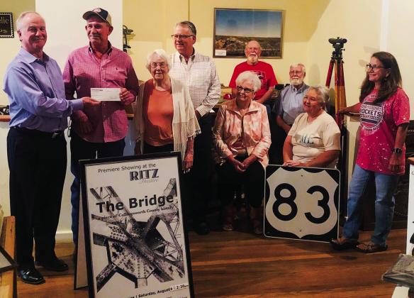 Wellington State Bank (WSB) President Richard Sims presents a $5,000 check to Collingsworth County Museum Board of Directors President Jeff Thomas. WSB is the sole sponsor for “The Bridge” documentary, which is set to be released on YouTube Friday, Nov. 4. From left, Sims, Thomas, Museum Director Doris Stallings, Neal Odom, Nancy Harris, Billy Wilkerson, Oran Sain, Geney Gulley and Assistant Museum Director Karen Caldwell. The Red River Sun/Bev Odom