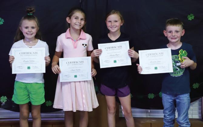Brynlee Holton, left, Jenna Faulks, Kaizley Byers and Braxton Sims earn Certificates of Completion for the Clover Kids program.