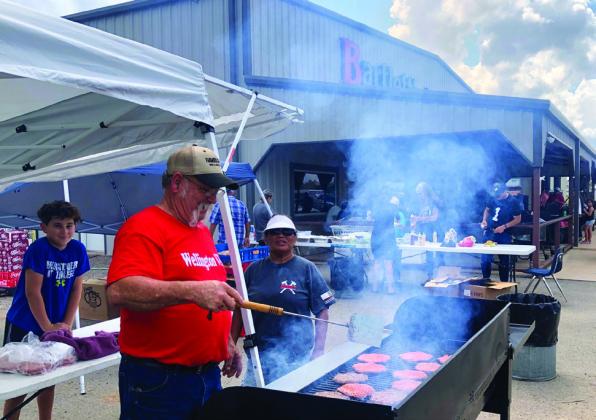 Wellington Volunteer Fire Chief Kevin Hamby, on behalf of the Wellington Volunteer Fire Department, grills hamburgers and hotdogs for the Labor Day weekend gala at Bartlett’s with assistance from his grandson, Jeremiah Hamby, and his wife, Eva Hamby.