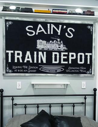The framed Sain’s Train Depot sign adds a focal point to the bedroom area, topped with a miniature replica of a train. Courtesy Photo