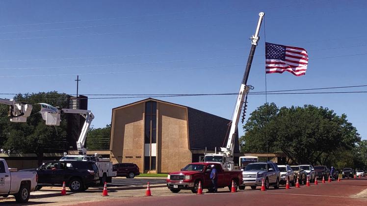 Members of Greenbelt Electric Cooperative, Inc. line 9th St. in Wellington Friday, Sept. 23 for the annual drive-thru meeting as Old Glory stretches out amongst powerlines. The Red River Sun/Bev Odom