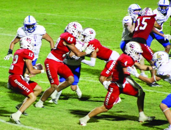Wellington quarterback Callen Kane (12) looks for room against Lubbock Christian Friday, Sept. 20 at Powell Field in Wellington, as the Skyrocket offensive line, including RJ Granadoz (60), Noah Cantu (4), Anthony Ortiz (15) and Brenden Garcia (1), hold the Eagles.