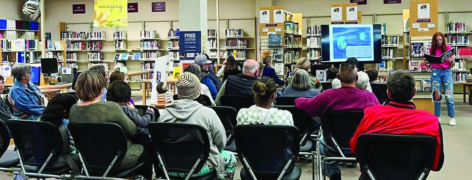 Family and friends listen as Bailey Page reads her published book, “The Dino-Bot Catastrophe,” illustrated by Christopher Reyes.