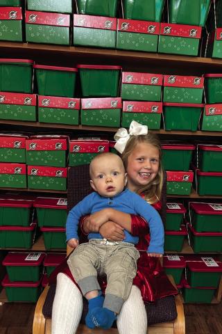 Lennox and Kellyn Conner, children of Tucker and Jordan Conner, complement the 117 Christmas shoeboxes, assembled by First Baptist Church Wellington, for Samaritan’s Purse Operation Christmas Child to be shipped to children in need around the world. The Red River Sun/Bev Odom