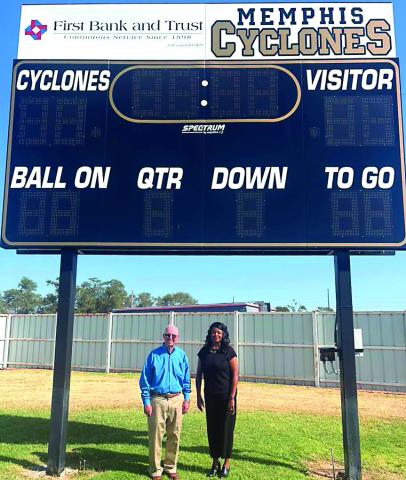 First Bank &amp; Trust President Steve Hall and Assistant Vice President Charolette Maddox stand under the new Cyclone Football scoreboard. The bank purchased the scoreboard that will elevate the game-day experience for Cyclone players, students, and fans alike. The new scoreboard reflects a shared dedication to celebrating local youth MISD PHOTO