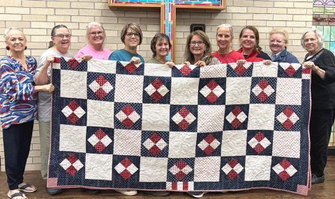 Wellington First Methodist Women, including Charlotte Stephens, Beckie Adams, Lori O’Rear, Donnie Carter, Janie Thomas, Karen Caldwell, Lisa Manuel, Amy Henard, Leslie Schnaufer Bell, and Sandy Sain, display the 2026 patriotic fundraiser quilt to be given away at the upcoming Saturday, Nov. 7 bazaar. INTREPID PHOTO / BEV ODOM