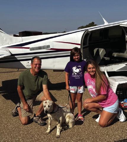 Volunteer pilot Bill Mastin, of Weatherford, delivers Farris from a shelter in East Texas to Wellington Sunday morning, Aug. 4. Wellington Rescue Shelter founder Andi Duke, right, and daughter Sherree, accept delivery of the heeler mix. Courtesy Photo